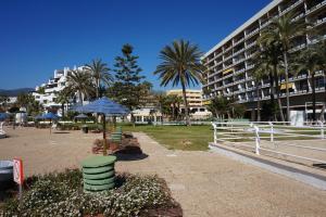 park z krzesłami, parasolem i budynkiem w obiekcie Castillo de Santa Clara w mieście Torremolinos