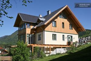 una casa grande con techo de gambrel en una colina en Landhaus Roidergütl, en St. Wolfgang