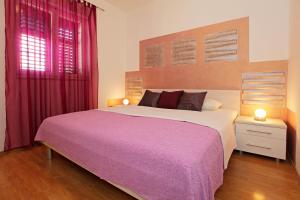 una camera da letto con un grande letto con una coperta viola di Katica apartments a Bol