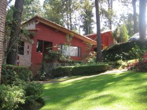 una casa roja con césped delante en La Casa del Rio, en Valle de Bravo