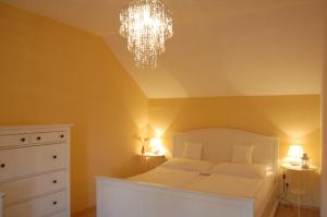 ein Schlafzimmer mit einem weißen Bett und einem Kronleuchter in der Unterkunft Hofgassl Zentgraf in Mörbisch am See