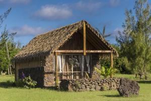 a small building with a stone wall in a field at Pacific Bungalows in Hanga Roa