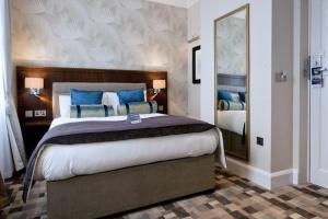 um quarto com uma cama grande e almofadas azuis em The Greenwood Hotel - Wetherspoon em Northolt