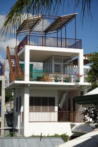 a large white building with a balcony and a palm tree at BJs Seaside in Argao