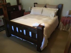 a bedroom with a large bed with white sheets at bluebird cottage in Angaston