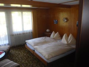 una camera da letto con un letto grande con lenzuola bianche di Hotel Milan B&B a Ringgenberg