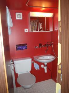 Baño rojo con aseo y lavamanos en Hotel Milan B&B, en Ringgenberg