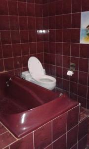 y baño con aseo y bañera roja. en Ratih Bali Hostel en Denpasar