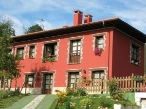 une maison rouge avec une clôture devant elle dans l'établissement Apartamentos Rurales Piedrafita, à Llenín