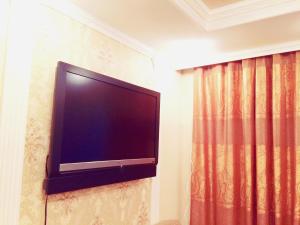 - une télévision à écran plat sur un mur à côté d'un rideau dans l'établissement Vremena Goda Apartment in Astana, à Astana