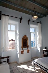 una camera da letto con due finestre, un letto e uno specchio di Suites Pandora a Chania