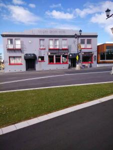 a white building with red windows on a street at Golden Cross Hotel in Waihi