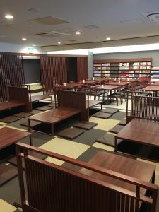 una biblioteca vacía con mesas de madera y libros en The Bed and Spa (male only) en Tokorozawa