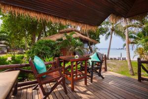 a deck with chairs and a table and a hut at Palm Leaf Resort Koh Tao in Ko Tao