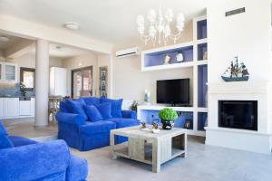 sala de estar con sofás azules y TV en Villa Thalassini, en Agia Efimia