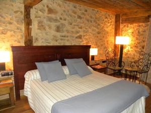 1 dormitorio con cama y pared de piedra en Posada Los Templarios, en Ucero