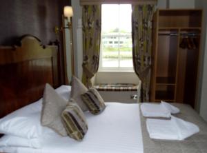 1 dormitorio con 1 cama con 2 almohadas y ventana en Wagon & Horses, en Lancaster