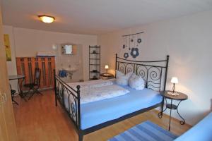 Schlafzimmer mit einem schwarzen Bett mit blauer Bettwäsche und einem Badezimmer in der Unterkunft Sendlerhof in Wenns