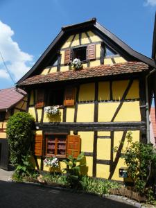 a yellow and black building with windows and flowers at La Maison Jaune in Vendenheim