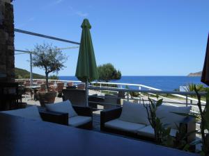 een patio met stoelen en een parasol en de oceaan bij Hotel Restaurant Le Filosorma in Galeria
