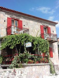 a building with red shutters and plants on it at Evanthia Toroz Rooms & Studios in Mythimna