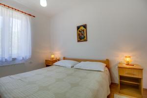 a bedroom with a bed with two night stands and a window at House Dorita in Miholašćica