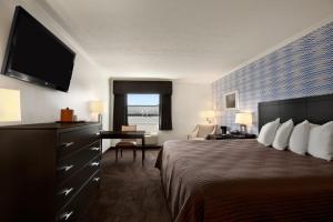 a hotel room with a bed and a flat screen tv at Travelodge by Wyndham Hubbard OH in Hubbard