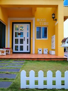 a yellow house with a white fence in front of it at Good Time in Magong