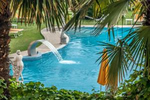 a swimming pool with a fountain in a resort at Hotel Terme Helvetia in Abano Terme