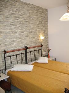 2 camas en una habitación con una pared de ladrillo en Iliovasilema, en Naxos Chora