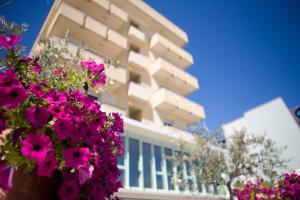 un edificio con fiori rosa di fronte di Hotel Palos a Rimini