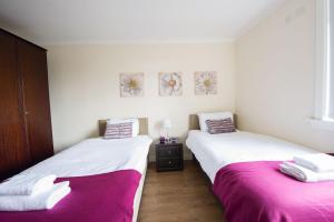 2 camas en una habitación con sábanas rosas y blancas en PREMIER - Park View Apartment, en Paisley