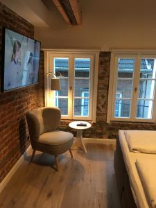 a bedroom with a bed and a chair and a tv at Square Rooms 20 in Düsseldorf