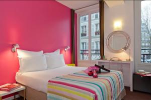 パリにあるHôtel Marais de Launayのピンクの壁のベッドが備わるホテルルームです。
