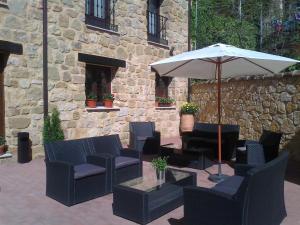 a patio with chairs and a table with an umbrella at Apartamentos Alameda in Sigüenza