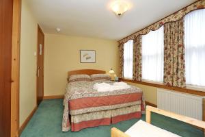 a bedroom with a bed in a room with windows at Butlers Guest House in Aberdeen