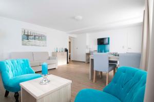 a living room with blue chairs and a table at Hotel Villa WellenRausch in Travemünde