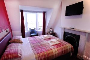 a bedroom with a bed with a fireplace and a television at Regent House Hotel - City Centre Hotel in Edinburgh