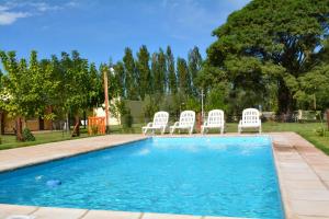 a group of white chairs sitting around a swimming pool at Ayres de Cuyo in San Rafael