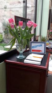 una scrivania con vaso di fiori rosa e un computer portatile di Hôtel République a Digione