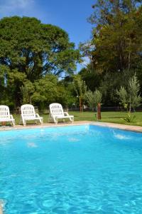 two white chairs sitting next to a swimming pool at Ayres de Cuyo in San Rafael