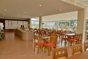 a restaurant with wooden tables and chairs and windows at Matsubara Pousada in Campos do Jordão