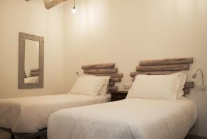 two beds in a room with white walls and a mirror at Hostal Gargal in Olvega