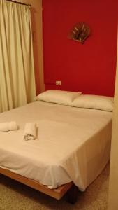 ein Schlafzimmer mit einem weißen Bett und einer roten Wand in der Unterkunft Residencial Castelar in Merlo