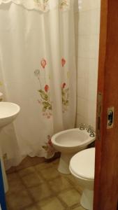 a bathroom with a toilet and a sink and a shower curtain at Residencial Castelar in Merlo