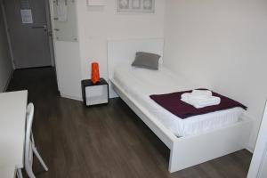 białe łóżko w pokoju z drewnianą podłogą w obiekcie Résidence Hôtelière Louise w Strasburgu