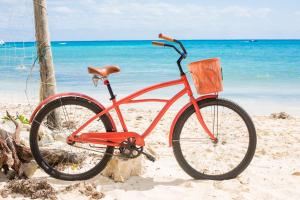a red bike parked on the beach near the ocean at Newport House Playa Boutique Hotel in Playa del Carmen