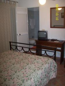 Dormitorio con cama, escritorio y TV en Albergo La Perla, en Orbetello