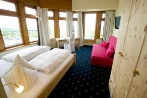 ヴィンターベルクにあるBobhaus Winterbergのベッド2台と赤いソファが備わるホテルルームです。