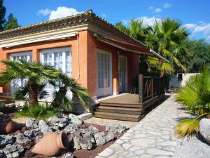 une petite maison avec une véranda et quelques palmiers dans l'établissement L'Oliveraie de Paul, à Aigues-Mortes